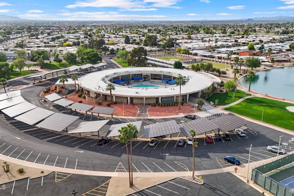 Aerial view highlights the impressive Sun City recreation center with community pool, landscaped grounds, walking paths, and gathering spaces conveniently located nearby.