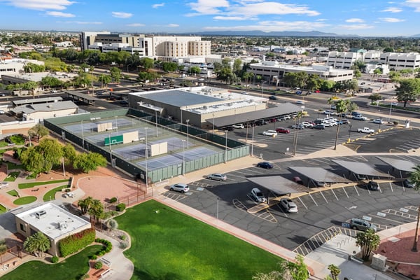 Elevated aerial view features nearby tennis courts, recreation buildings, landscaped green spaces, and convenient neighborhood amenities, showcasing the outstanding lifestyle available in Sun City.