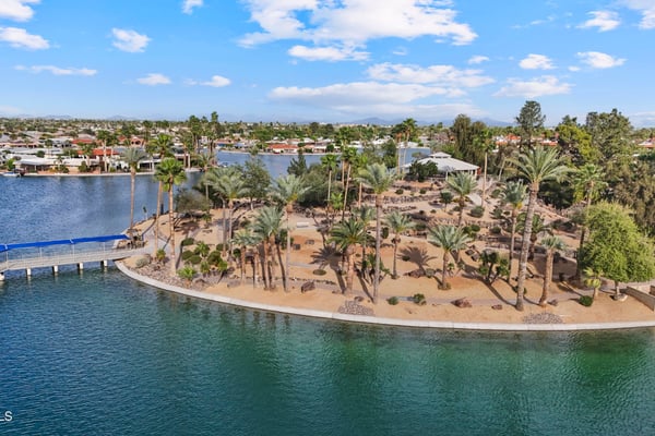 Scenic aerial highlights lakeside walking paths, mature palm trees, landscaped park areas, and peaceful waterfront surroundings. Sun City offers exceptional outdoor spaces just minutes away.