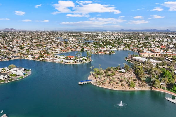 Expansive aerial showcases the nearby lake, waterfront homes, mature landscaping, and inviting neighborhood surroundings. Enjoy the scenic beauty that makes Sun City a desirable place to call home.