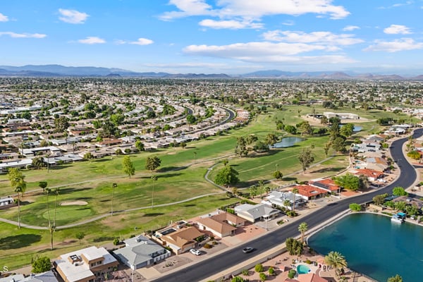 Sweeping aerial view highlights the nearby golf course, fairways, greens, and surrounding neighborhood. Enjoy easy access to premier golf and beautiful outdoor scenery in Sun City.