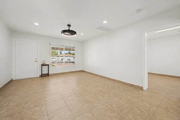 Bright interior living room with recessed lighting, tile flooring, neutral finishes, and generous natural light, creating a versatile gathering space ready for your personal style.