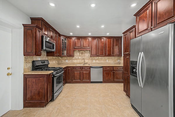 Well-appointed kitchen featuring extensive wood cabinetry, granite countertops, stainless steel appliances, decorative tile backsplash, and abundant prep space designed for both cooking and entertaining.