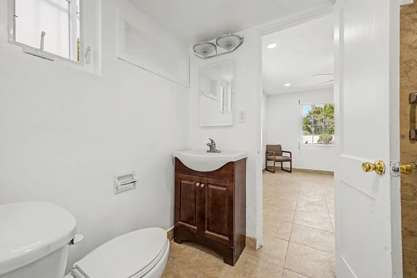 Functional bathroom vanity area with a wood vanity cabinet, modern sink, mirror, natural light, and direct access to the connected bedroom. Clean finishes and practical storage enhance the everyday convenience of this Phoenix home.