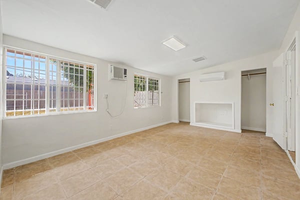 Spacious bedroom featuring large windows, tile flooring, mini-split air conditioning, open closet alcoves, and abundant natural light. This inviting retreat offers flexibility and everyday comfort in this Phoenix home.