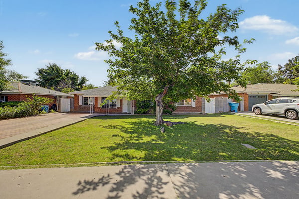 Front exterior features timeless brick construction, a mature shade tree, spacious lawn, and inviting front entry. This attractive setting creates lasting curb appeal for the Phoenix property.