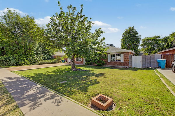 Beautiful front yard with established trees, green lawn, and wide driveway enhances the home's welcoming appearance. A classic exterior complements this well-maintained Phoenix residence.