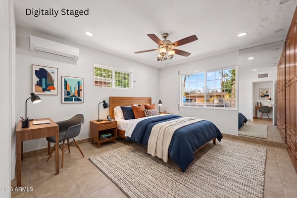 Digitally staged owner's suite featuring stylish furnishings, dedicated workspace, custom built-in storage, large windows, and an inviting layout that showcases the room's size and flexibility in this Phoenix property.
