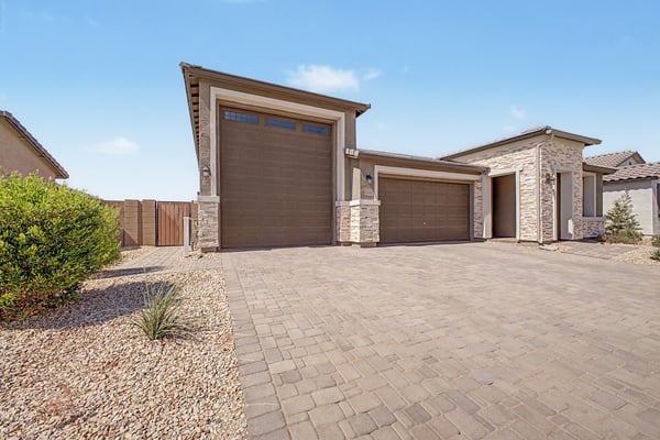 Angled view highlighting the oversized RV garage, wide paver driveway, and attractive exterior finishes. An ideal home for outdoor enthusiasts, hobbyists, or anyone needing exceptional garage space.