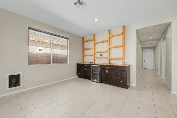 Versatile room with custom built-ins, beverage refrigerator, generous storage, and decorative shelving. Perfect for entertaining, displaying collectibles, or creating a stylish home workspace.