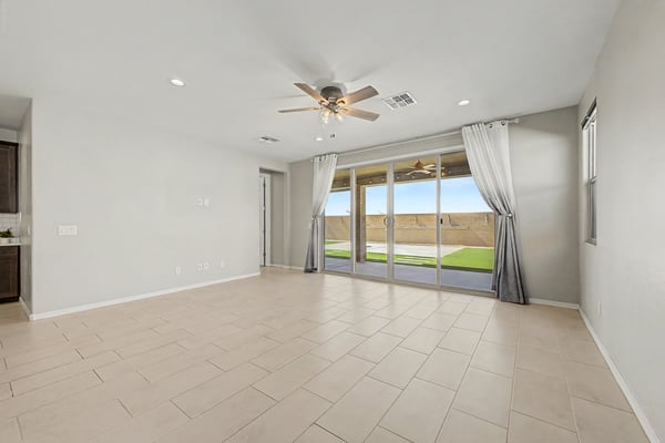 Expansive great room with oversized sliding glass doors, recessed lighting, and durable tile flooring opens to the covered patio and low-maintenance backyard, creating a seamless indoor-outdoor living experience.