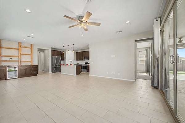 Open-concept living area featuring durable tile flooring, abundant natural light, custom built-in cabinetry with beverage refrigerator, and seamless flow into the gourmet kitchen. Perfect for entertaining and everyday living.