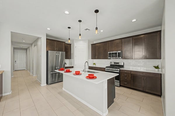 Modern kitchen featuring quartz countertops, a large center island, stainless steel appliances, subway tile backsplash, and extensive cabinetry. Designed for cooking, entertaining, and gathering with family and friends.
