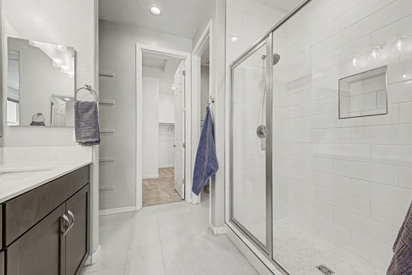 Modern primary bath featuring a beautifully tiled walk-in shower with glass enclosure, built-in storage niche, quartz vanity, and upscale finishes. A clean, contemporary space designed for daily comfort and relaxation.