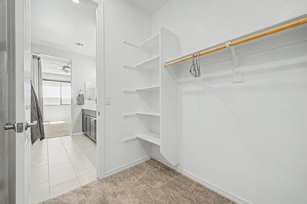 Spacious walk-in closet featuring built-in shelving, dedicated hanging space, and direct access to the primary bathroom. Designed to maximize storage while keeping everyday essentials organized.