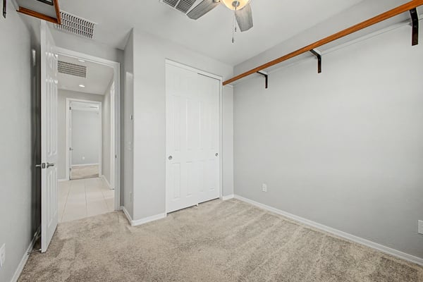 Spacious guest bedroom featuring soft carpeting, ceiling fan, generous closet, and neutral finishes. A welcoming space offering flexibility for family, visitors, or remote work.