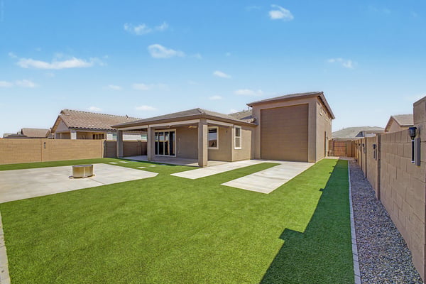 Rear elevation showcasing the covered patio, oversized RV garage, low-maintenance artificial turf, and expansive outdoor living spaces. A backyard designed to maximize comfort and functionality.