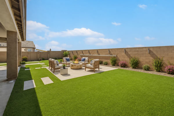 Virtually Staged Beautifully landscaped backyard with premium artificial turf, expansive patio space, decorative stepping stones, and a covered outdoor living area. A perfect setting for relaxing, entertaining, and enjoying the Arizona lifestyle in Wittman.
