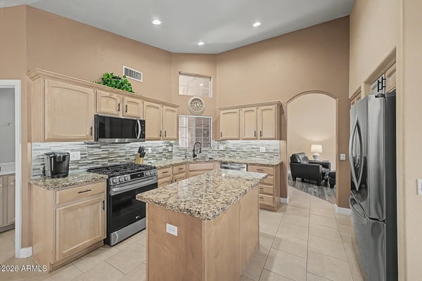 Prepare meals with ease in this spacious kitchen featuring granite countertops, stainless steel appliances, generous cabinetry, recessed lighting, and a large island designed for gathering and entertaining.