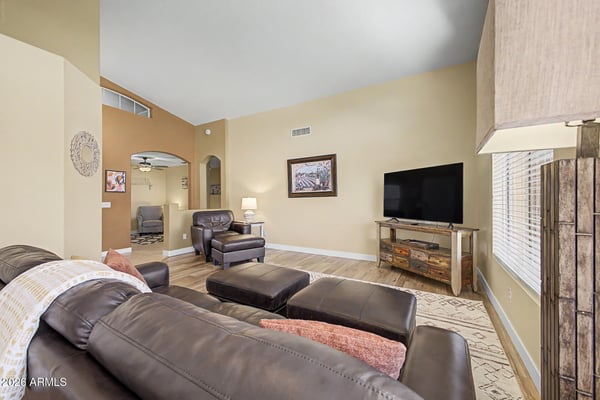 The spacious family room offers wood-look flooring, vaulted ceilings, abundant natural light, and an open layout perfect for relaxing, entertaining, or spending time with family in this Goodyear rental.