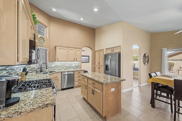 Designed for convenience, this open kitchen features granite countertops, stainless steel appliances, ample cabinet storage, tile flooring, and a center island that anchors the living and dining spaces.