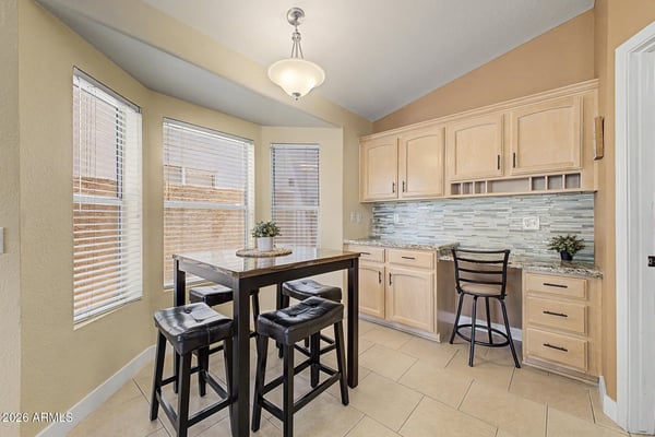 Enjoy meals or work from home in this sunny breakfast nook featuring bay windows, built-in cabinetry, and a convenient workspace. Natural light enhances the comfortable atmosphere throughout the day.