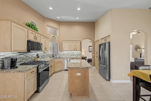 Featuring granite countertops, stainless steel appliances, a decorative tile backsplash, recessed lighting, vaulted ceilings, and a spacious island, this beautifully updated kitchen is designed for effortless entertaining and daily living.