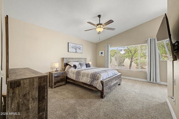 Enjoy a spacious owner's suite featuring vaulted ceilings, plush carpet, oversized windows, and peaceful backyard views. This comfortable bedroom offers the perfect place to relax at the end of the day.