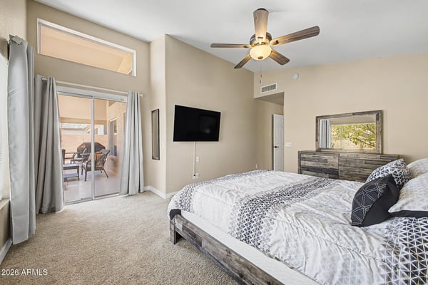The spacious primary bedroom features vaulted ceilings, soft carpeting, patio access, and abundant natural light. A relaxing retreat designed for comfort and everyday living.
