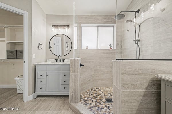 Experience luxury in the renovated primary bathroom featuring a custom tile shower, frameless glass enclosure, modern vanity, updated lighting, and elegant designer finishes throughout.