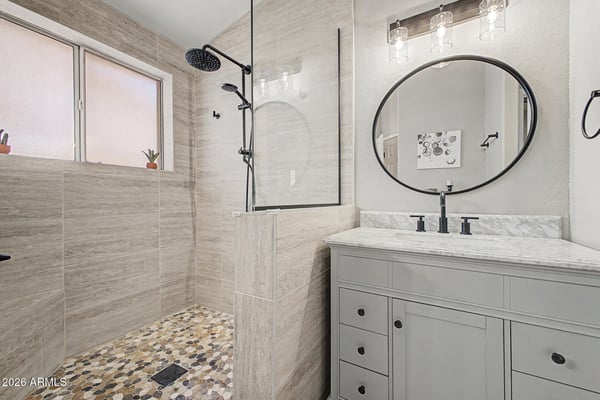 Beautifully upgraded with custom tile, a frameless glass shower, rainfall showerhead, pebble flooring, and contemporary vanity, this bathroom combines style and functionality for everyday comfort.