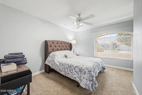 Featuring plush carpeting, neutral colors, and a large window, this welcoming bedroom offers a comfortable space for overnight guests, family members, or a private office.
