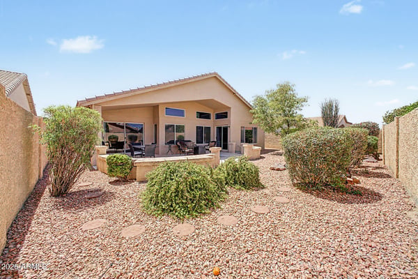 This inviting backyard combines mature landscaping, decorative rock, privacy fencing, and a large covered patio to create a peaceful outdoor retreat with minimal maintenance.
