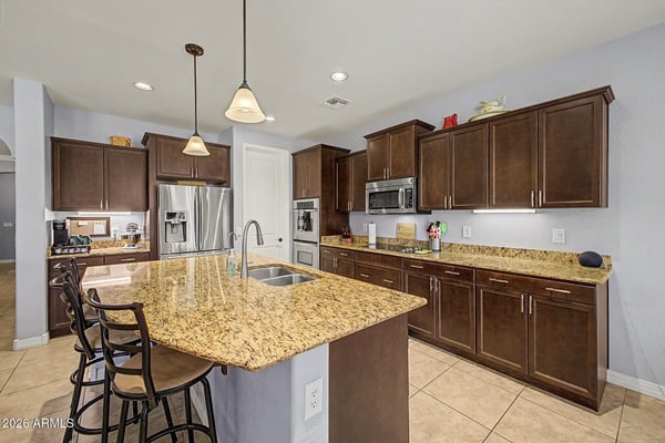 Prepare meals with ease in this spacious kitchen featuring granite countertops, stainless steel appliances, abundant cabinetry, a large island with seating, and a walk-in pantry. An ideal space for entertaining and everyday living.