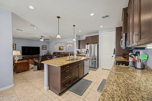 Designed for everyday living and entertaining, this gourmet kitchen features granite countertops, stainless steel appliances, a spacious island, abundant cabinetry, and a walk-in pantry with plenty of storage.