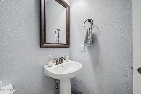 This beautifully maintained powder room offers a pedestal sink, framed mirror, and contemporary fixtures, providing guests with comfort and convenience while complementing the home's elegant finishes.
