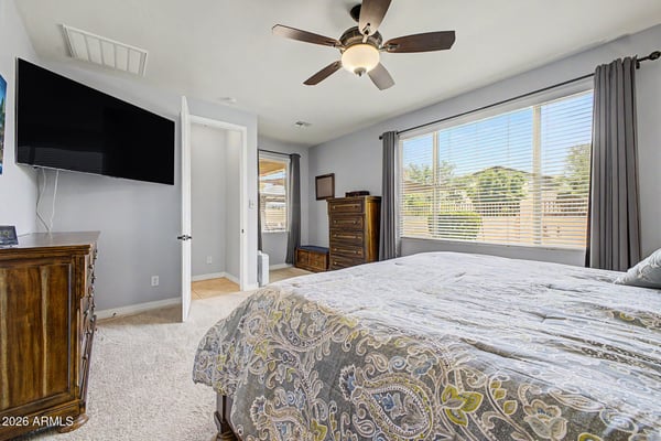 Oversized windows fill the owner's bedroom with natural light while plush carpet, ceiling fan, and generous proportions provide everyday comfort in this beautiful rental home in Goodyear.
