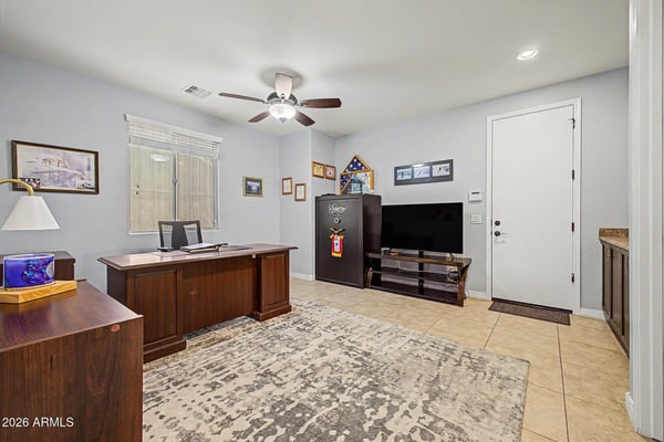 Designed for flexibility, this spacious room works beautifully as a home office, media room, or hobby space with built-in cabinetry, tile flooring, and abundant natural light in Goodyear.