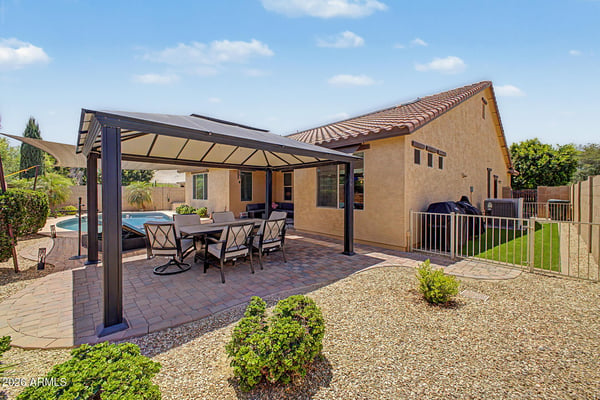 Another view showcases the spacious covered patio, attractive paver surfaces, and beautifully maintained backyard that complements the private pool in this Goodyear rental home.