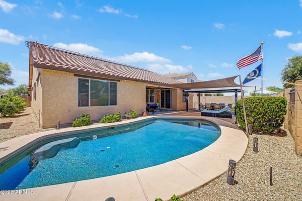 A sweeping backyard view highlights the private swimming pool, covered entertainment pavilion, paver patio, and professionally maintained landscaping, creating an exceptional outdoor retreat in Goodyear.