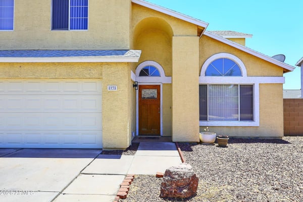 Covered entrance features an attractive wood front door, elegant archways, and inviting architectural details that enhance this Phoenix rental's curb appeal.