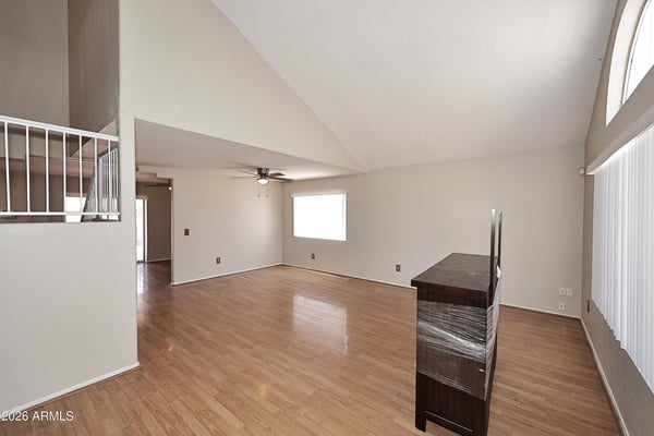 Formal living room features dramatic vaulted ceilings, expansive windows, updated flooring, and versatile space perfect for entertaining guests.