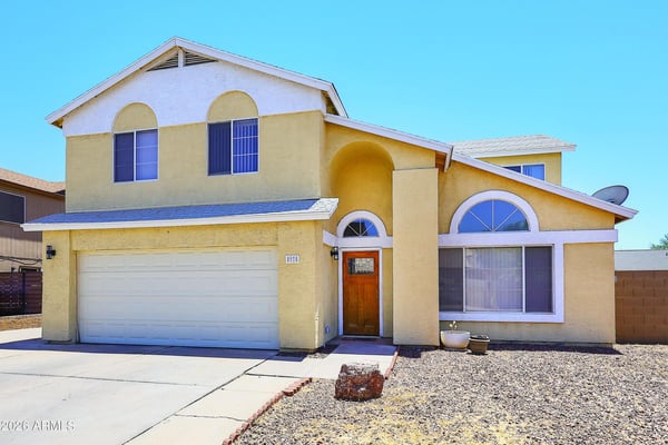 Corner perspective highlights the home's impressive architecture, attached garage, spacious driveway, and inviting front entry with easy access to nearby conveniences.