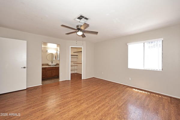 Spacious primary suite features updated flooring, ceiling fan, abundant natural light, and direct access to a large walk-in closet and private bath.