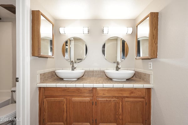 Spacious ensuite bathroom features dual vessel sinks, abundant cabinet storage, and a functional vanity designed for busy mornings.