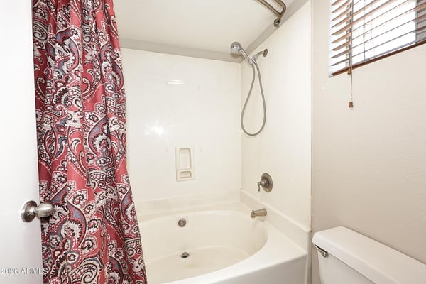 Private bathroom includes a full tub and shower combination with natural light and a practical layout that complements the spacious primary suite.