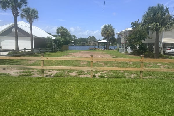 Scenic waterfront lot with potential for building, surrounded by palm trees and nearby waterfront homes.