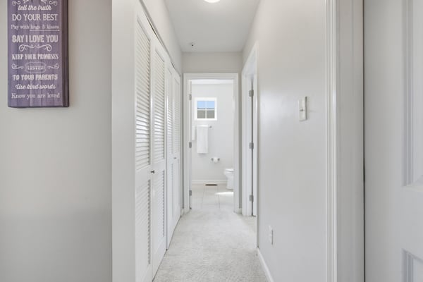 Bright and airy hallway leading to well-appointed rooms, featuring soft carpeting and convenient layout.