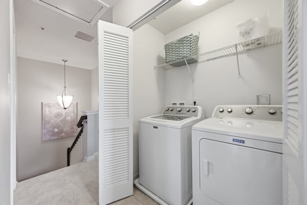 Conveniently located laundry area features modern appliances and practical shelving for organized storage.
