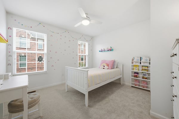 Bright and airy bedroom with ample natural light, featuring a cozy bed and playful decor.